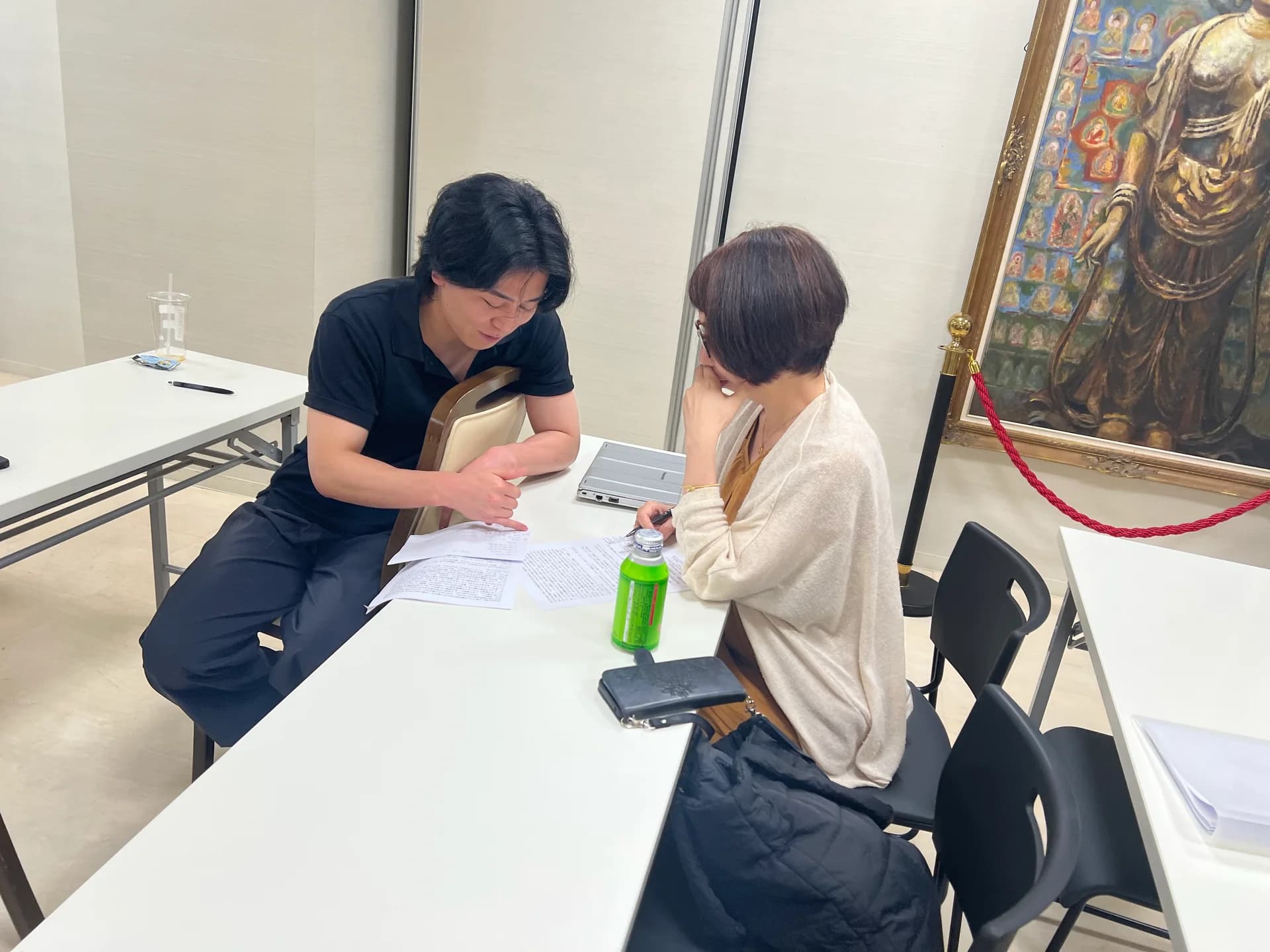 机を挟み、資料を見ながら対話する二人(過去の活動風景)
