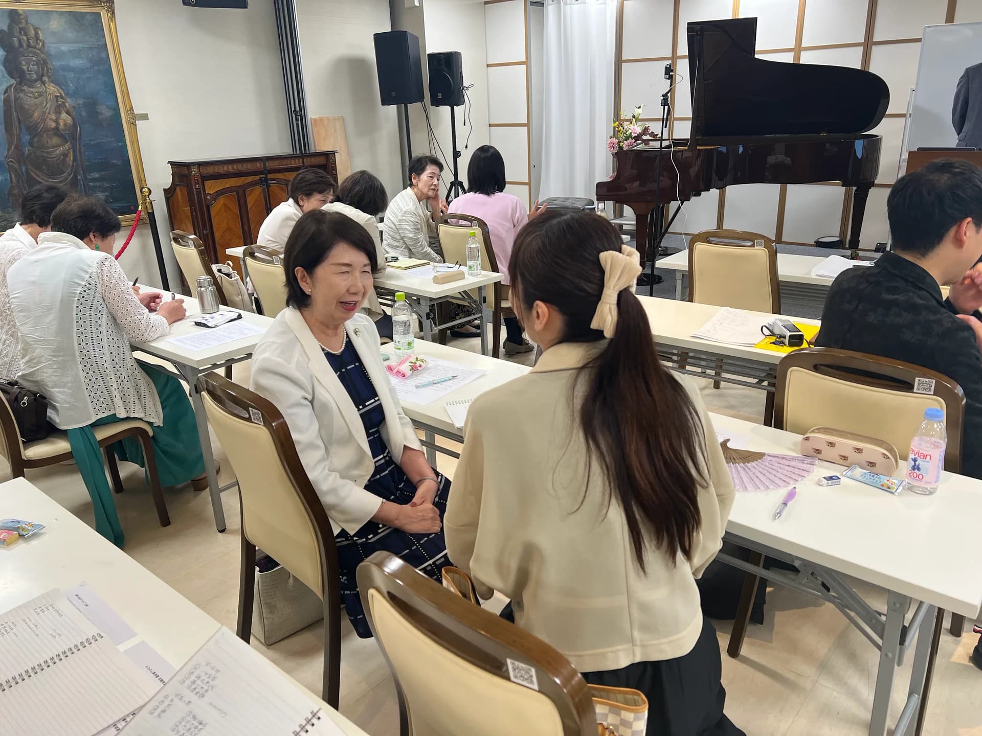 会場の机を挟み、互いの話に耳を傾ける参加者(過去の活動風景)